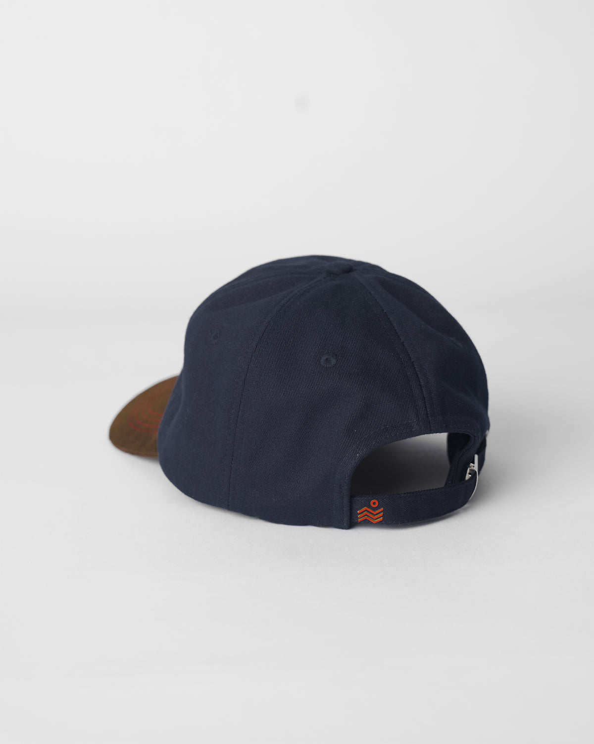 Back of a navy Starry Cap showing the adjustable strap and orange logo.