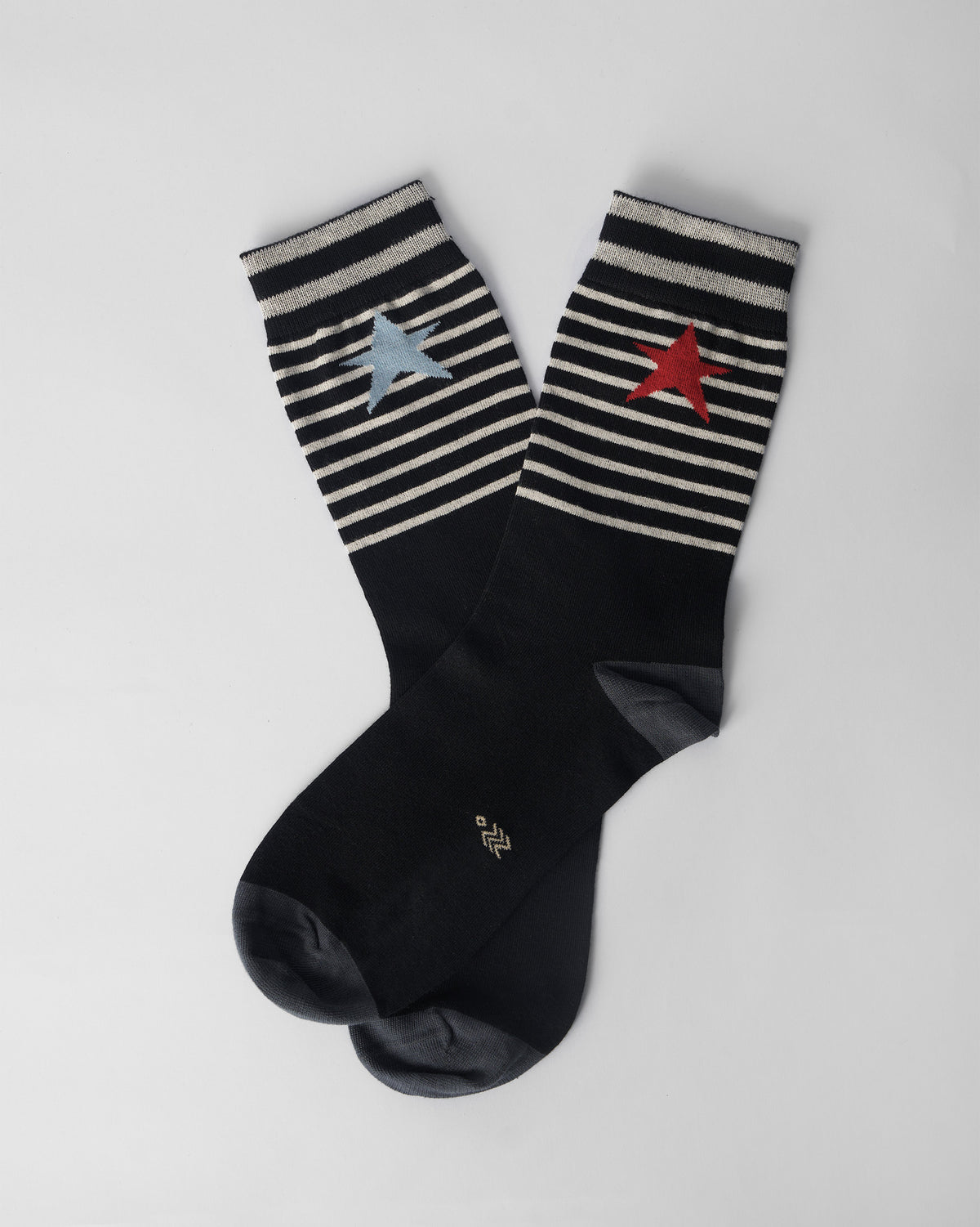 Black Starfly socks crossed flat, showing stripes and mismatched stars.