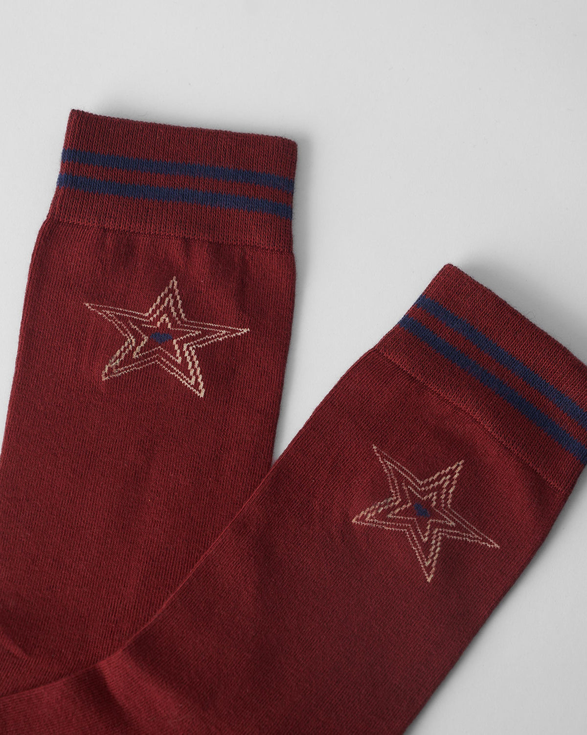 Close-up of maroon sock cuffs with navy stripes and cream star embroidery.