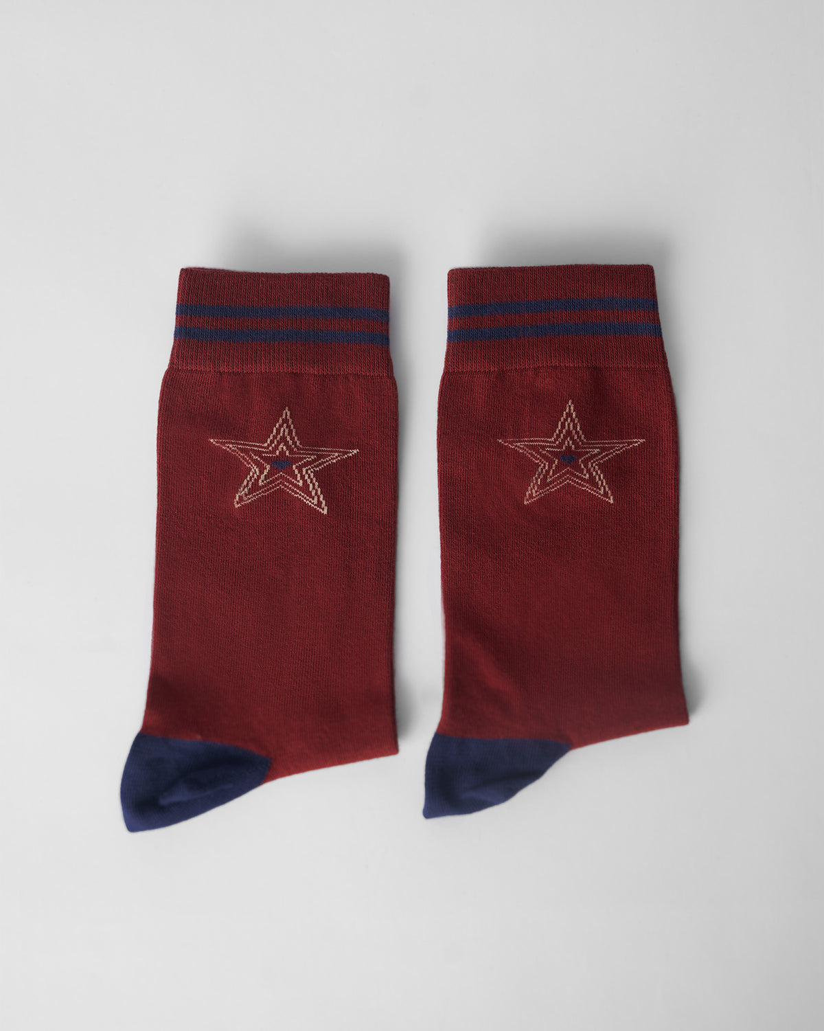 Pair of maroon Starry socks laid flat with navy heels and star motifs.