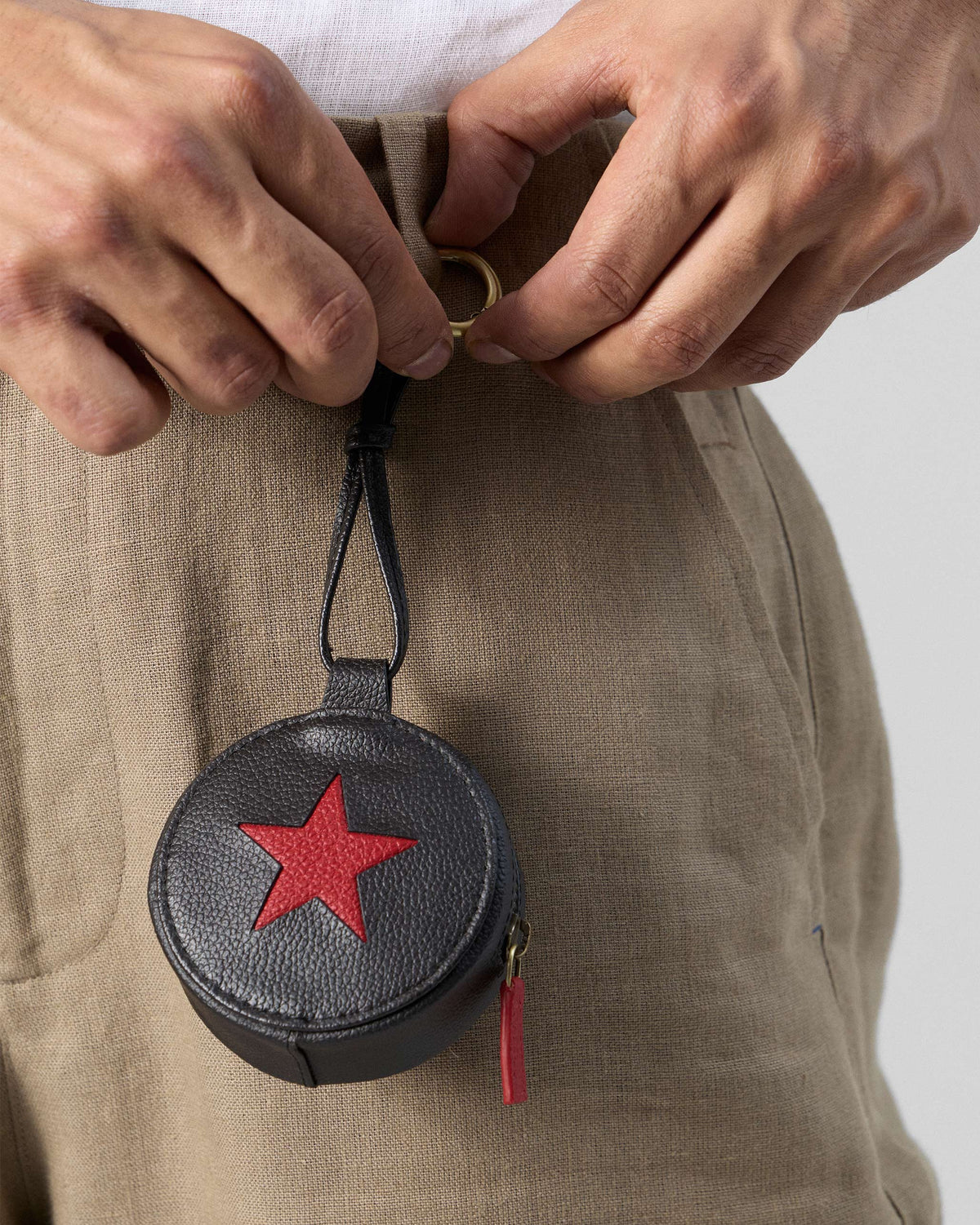 Black and red Nova Charm with a red star clipped to a belt loop.