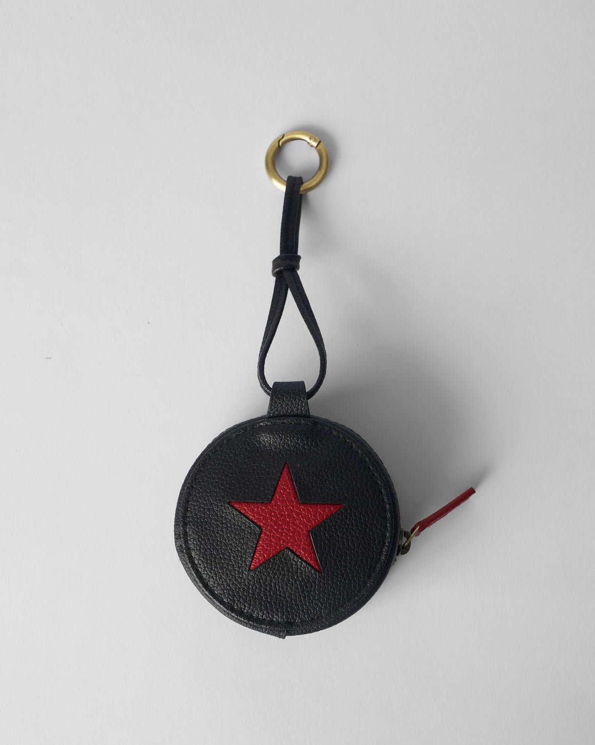 Black Nova Charm with a red star and brass clip ring.