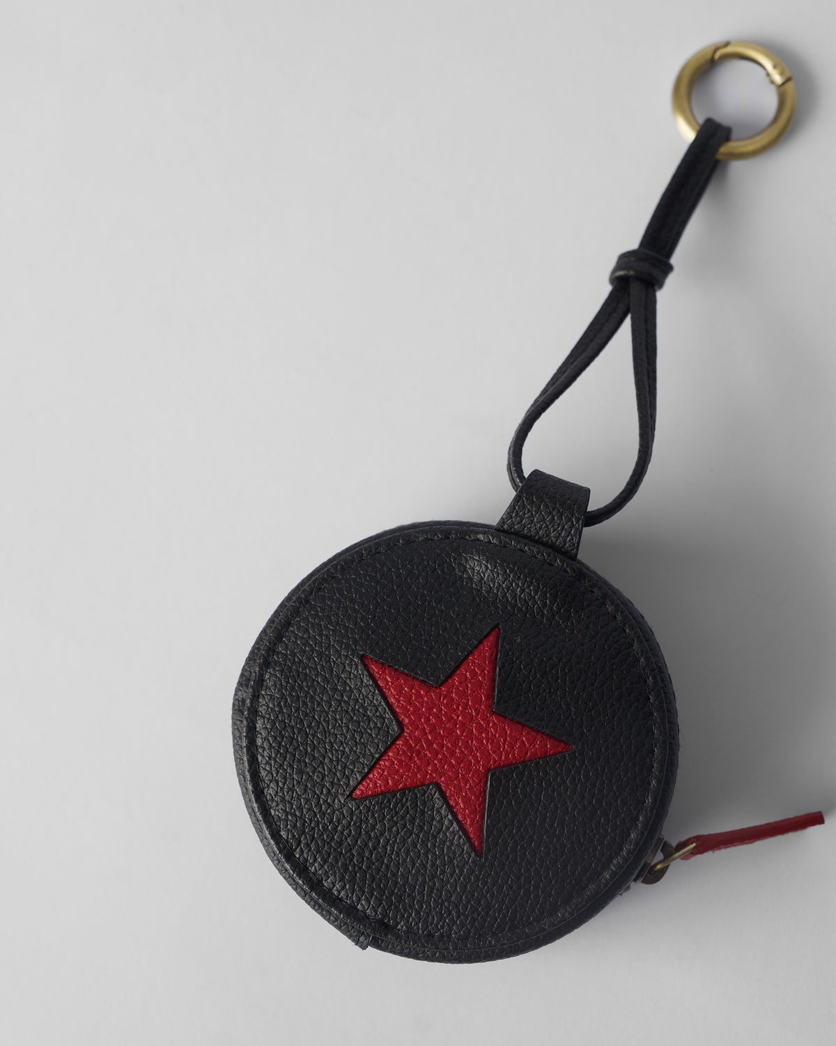 Black Nova Charm with a red star and open brass clip ring.