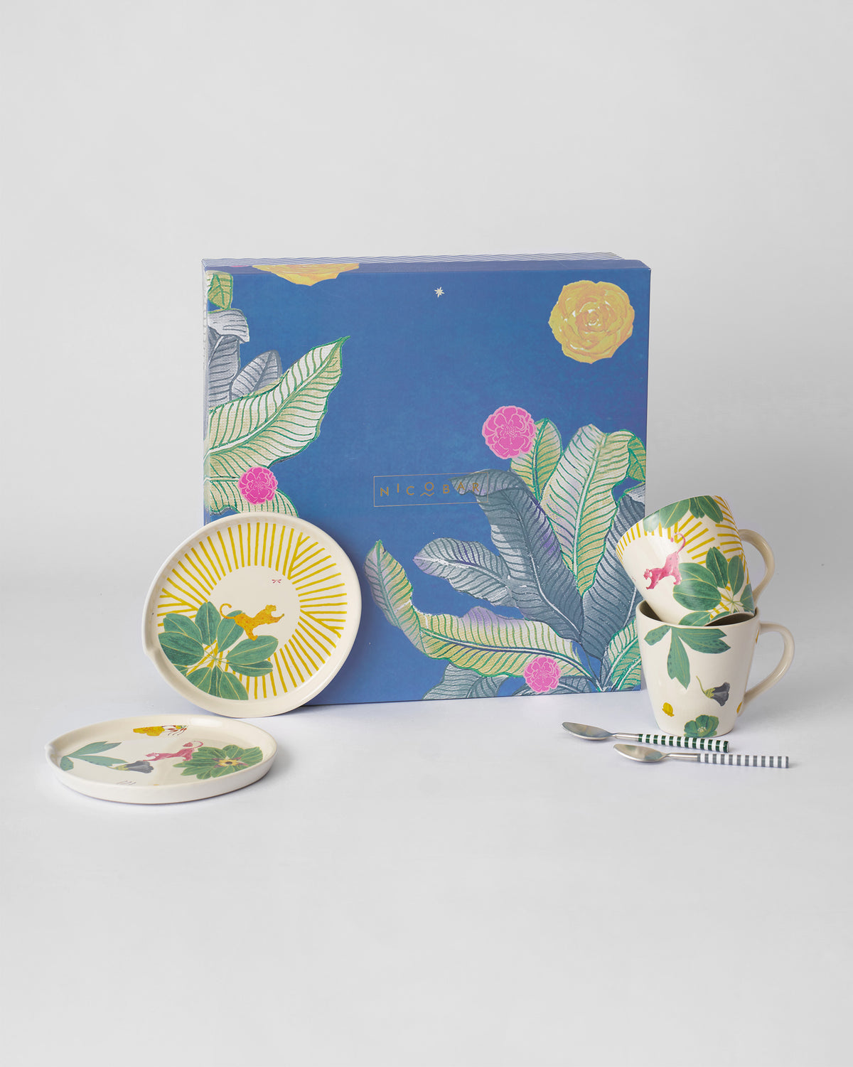 Waadi gift set with tropical plates, conical mugs, striped spoons, and blue box.
