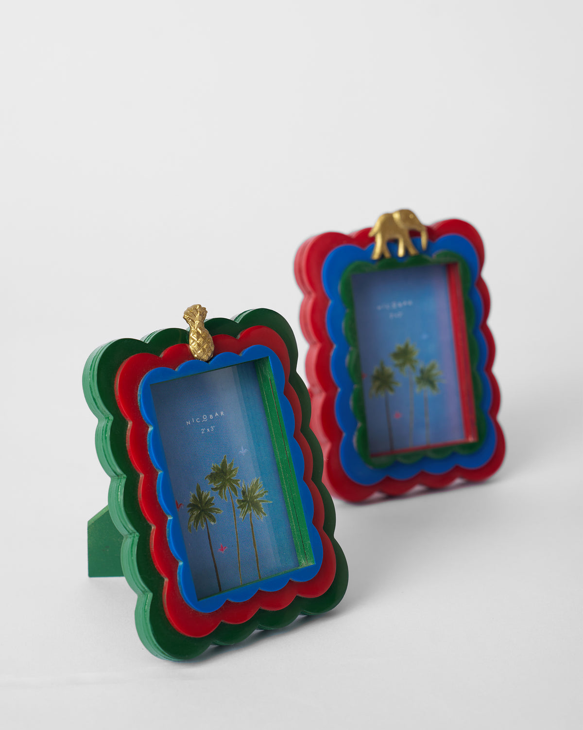 Tropics photo frames topped with gold pineapple and elephant charms.