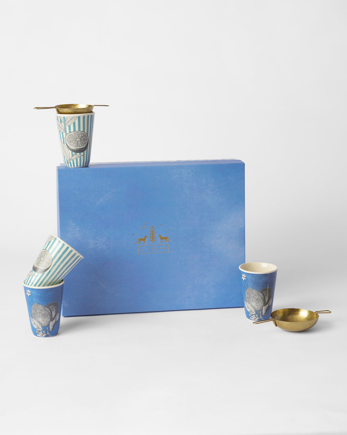 Neel gift set of blue citrus kulhars and brass strainers around a light blue gift box.