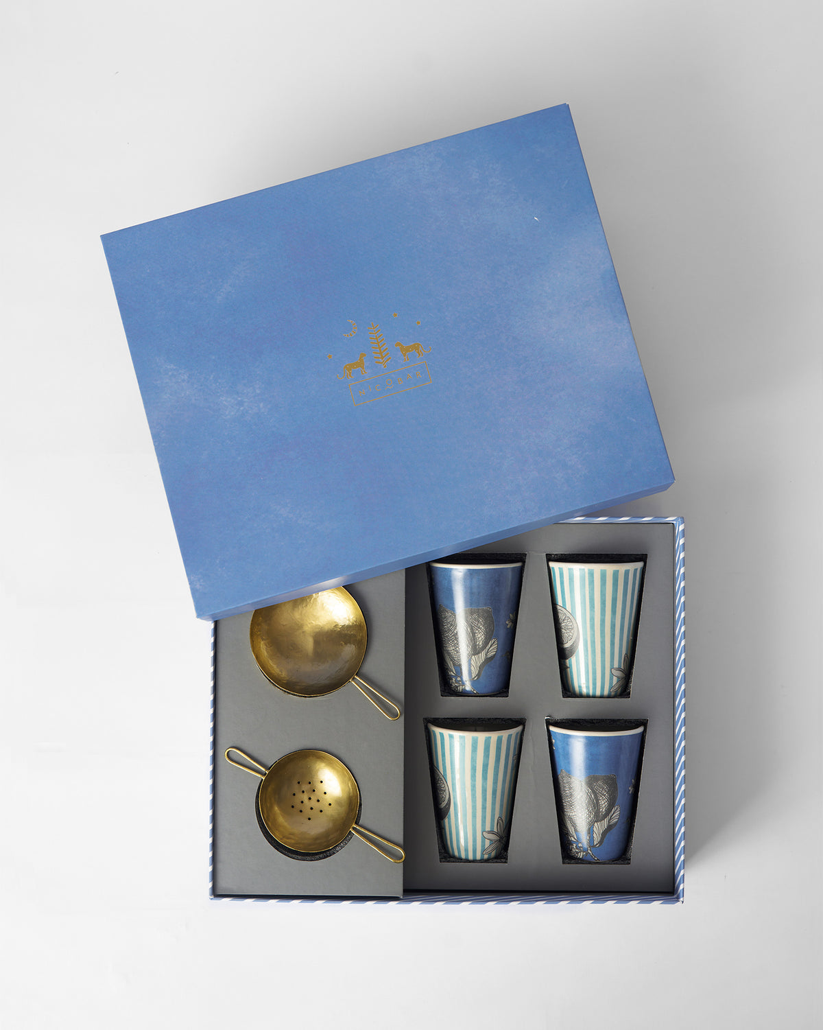 Neel kulhars and brass strainers nestled in an open blue gift box insert.