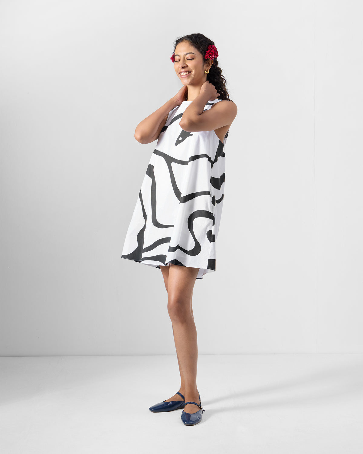 Person wearing a black printed short racerback dress with a bold curved print.