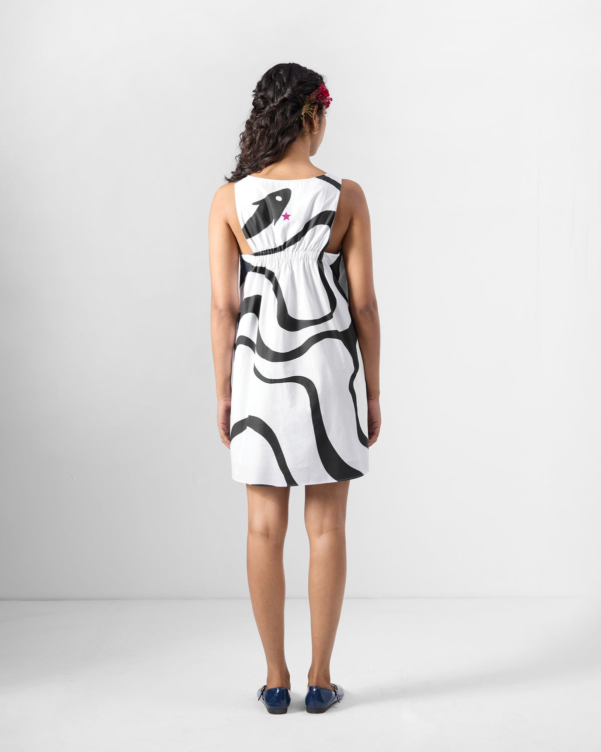Back of a black printed short racerback dress with a scoop and a pink star.