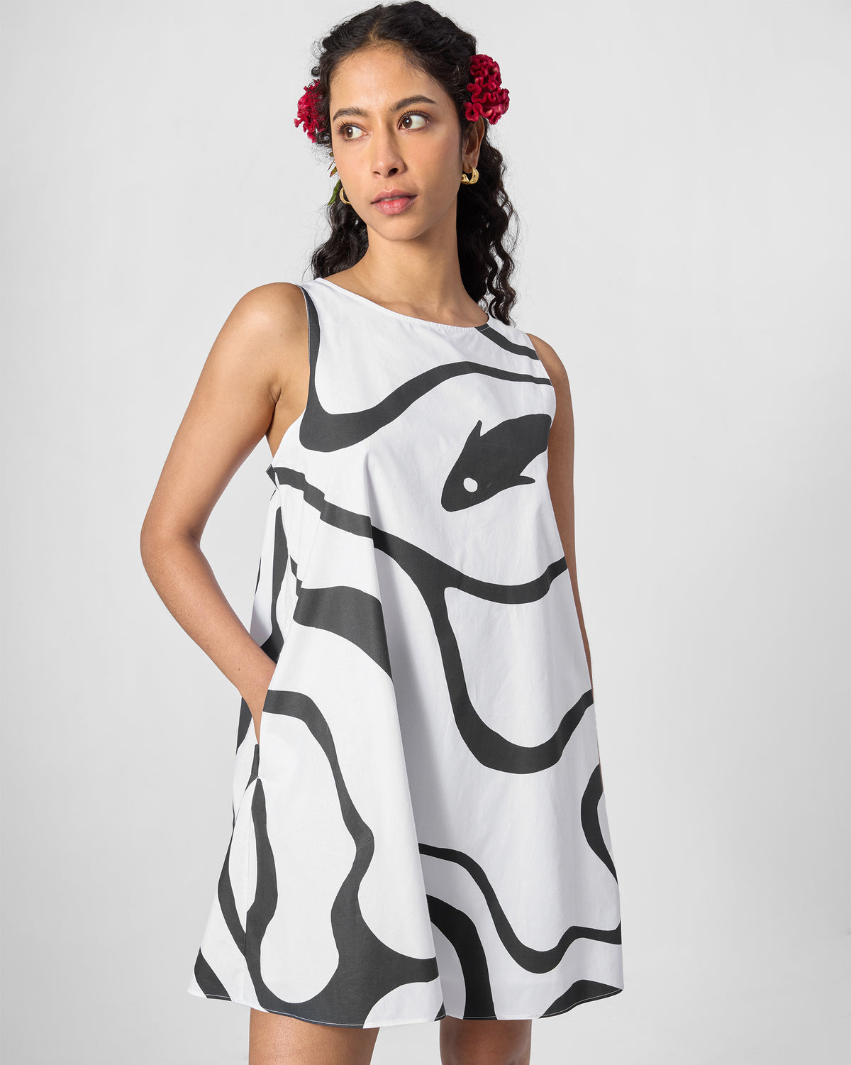 Person wearing a black printed short racerback dress with a side pocket.