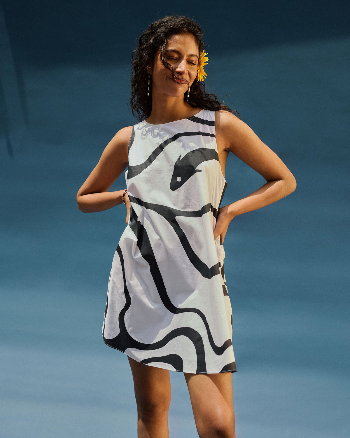 Person wearing a black printed short racerback dress with a fish motif on the chest.