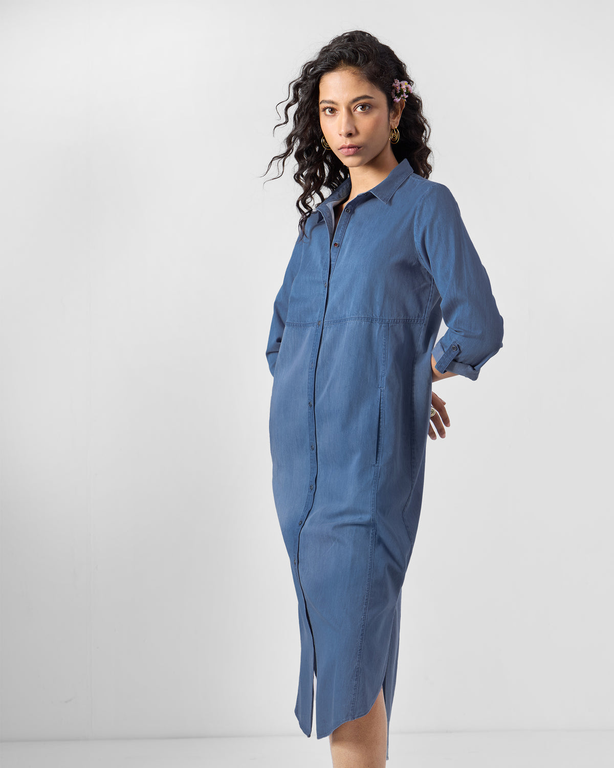 Person wearing a blue Pristine shirt dress with rolled sleeves.