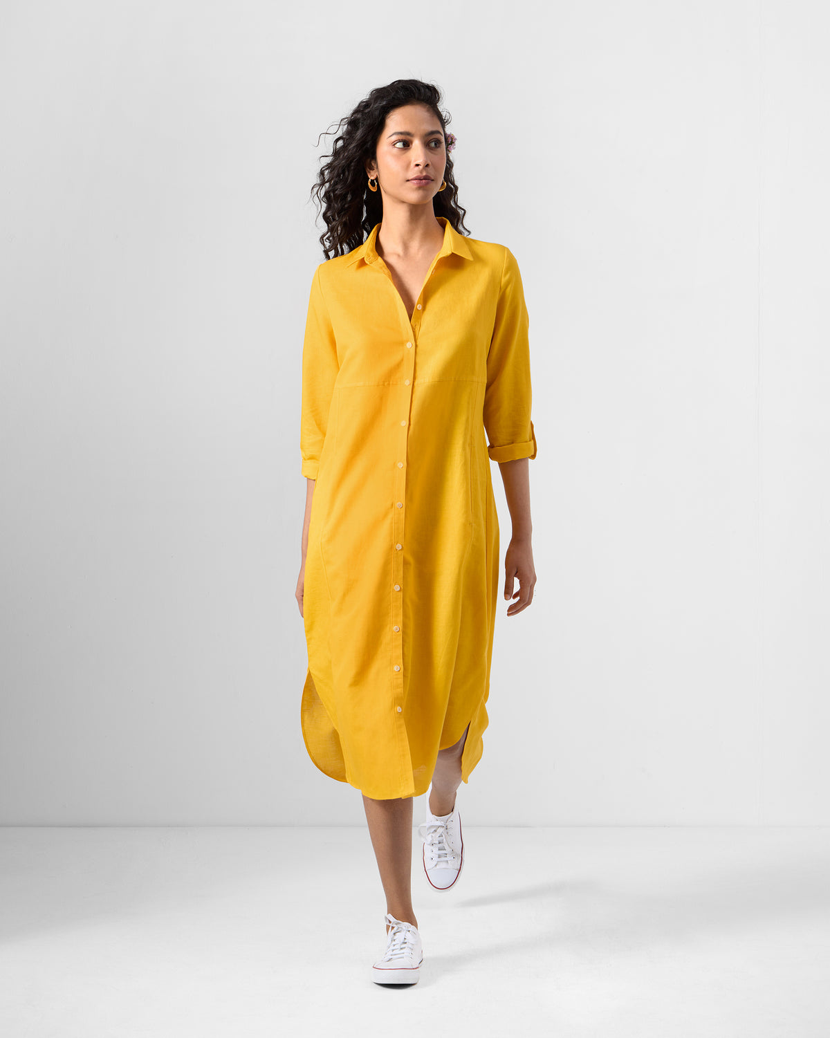 Person wearing an ochre Pristine dress with a shirt collar and midi hem.