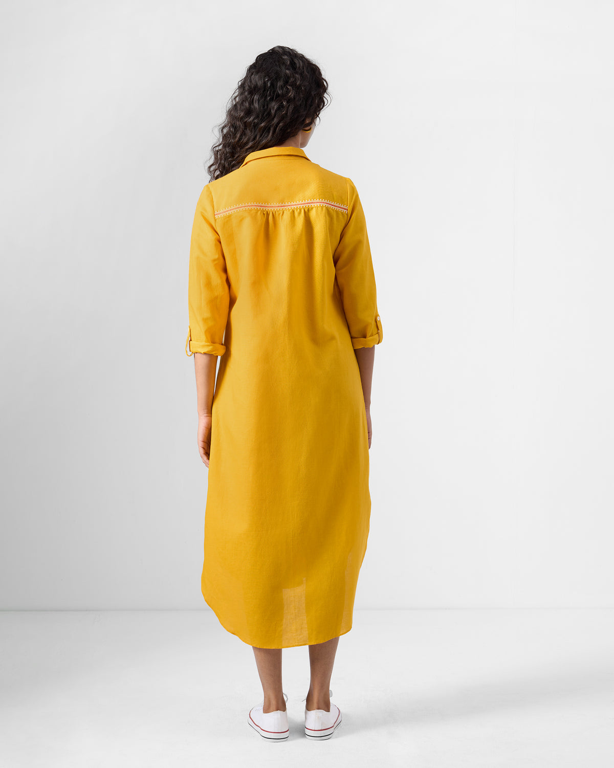 Back of an ochre Pristine dress showing the yoke detail and longer back hem.