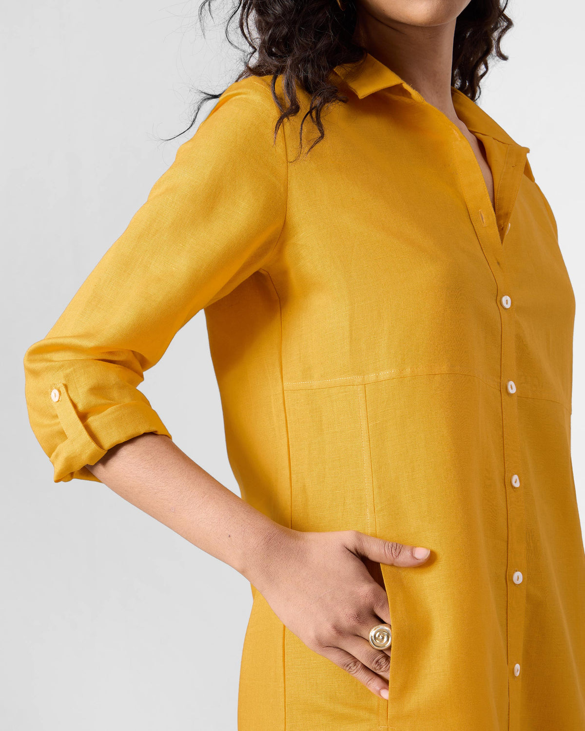 Side view of an ochre Pristine dress showing the side pocket and rolled sleeve.