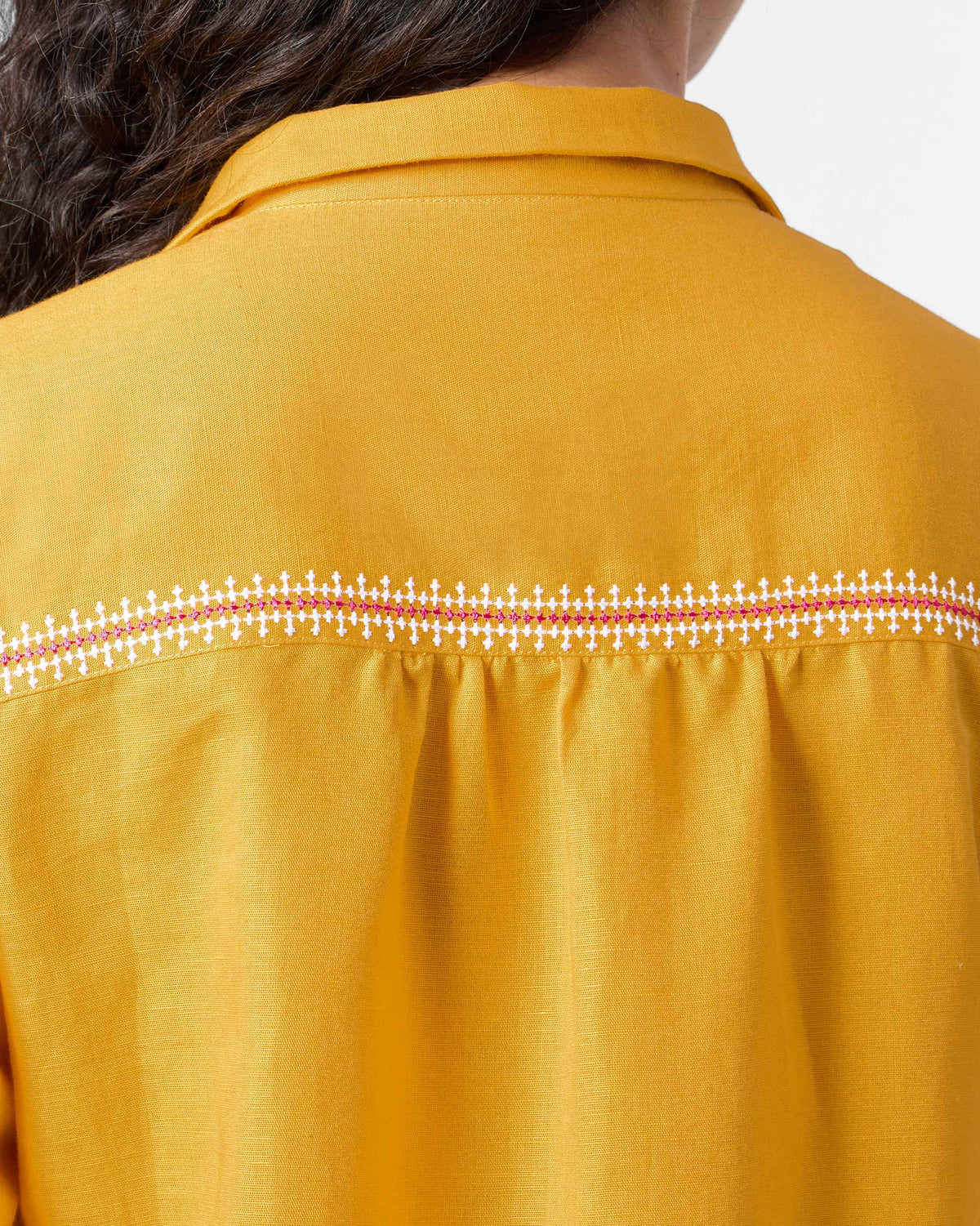 Close-up of the embroidered back yoke on an ochre Pristine dress.