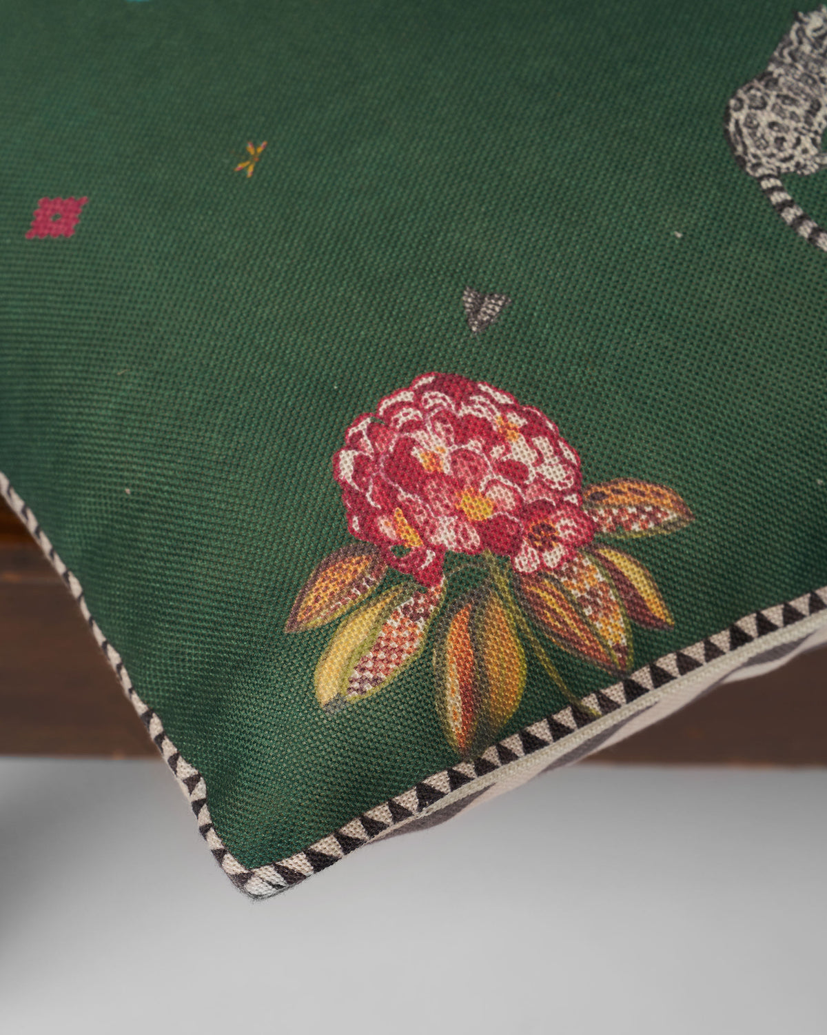 Close-up of the Kingfisher Bloom cushion cover showing a red flower and piped edge.