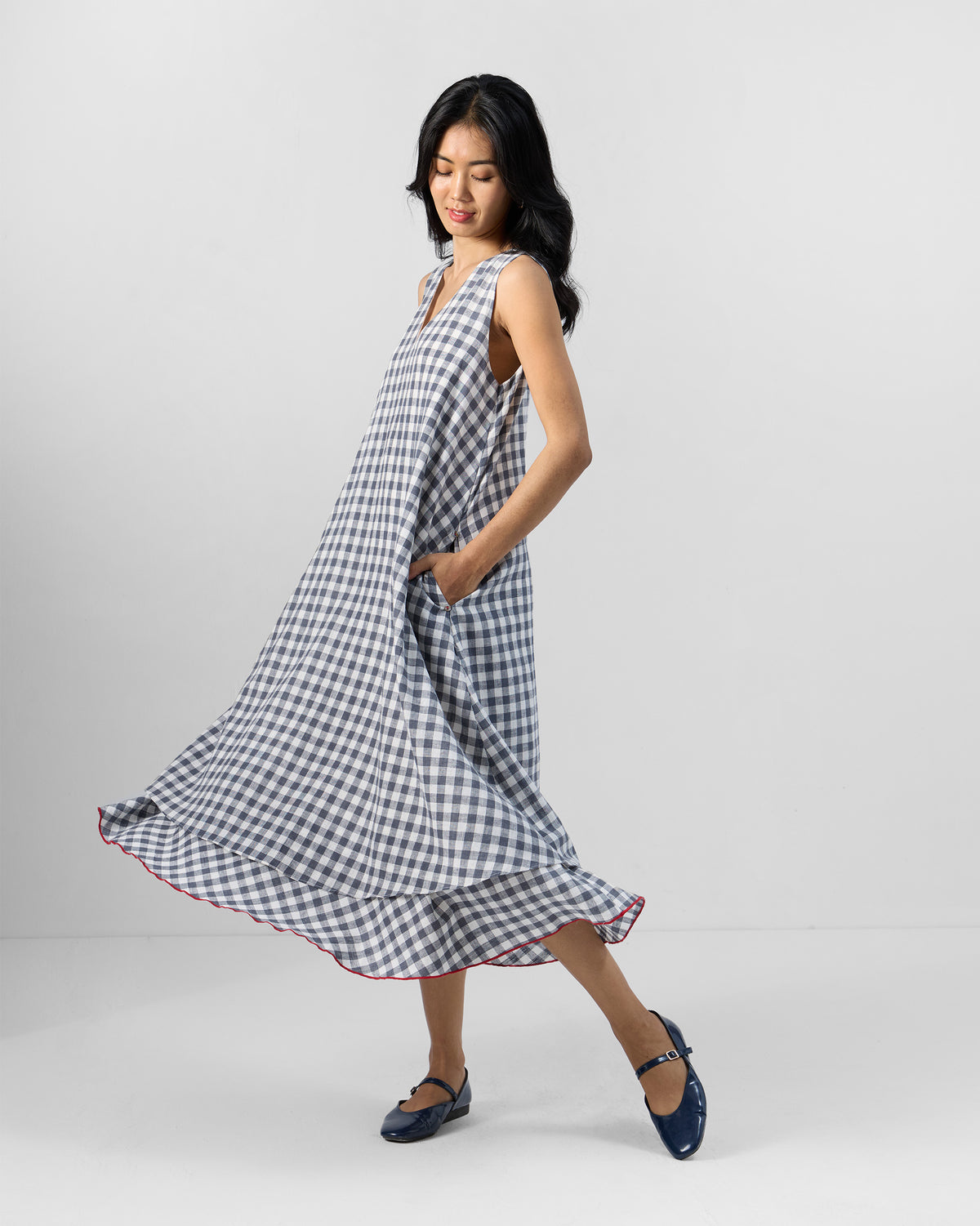 Person wearing a grey and white check Ezra dress with a red hem trim.