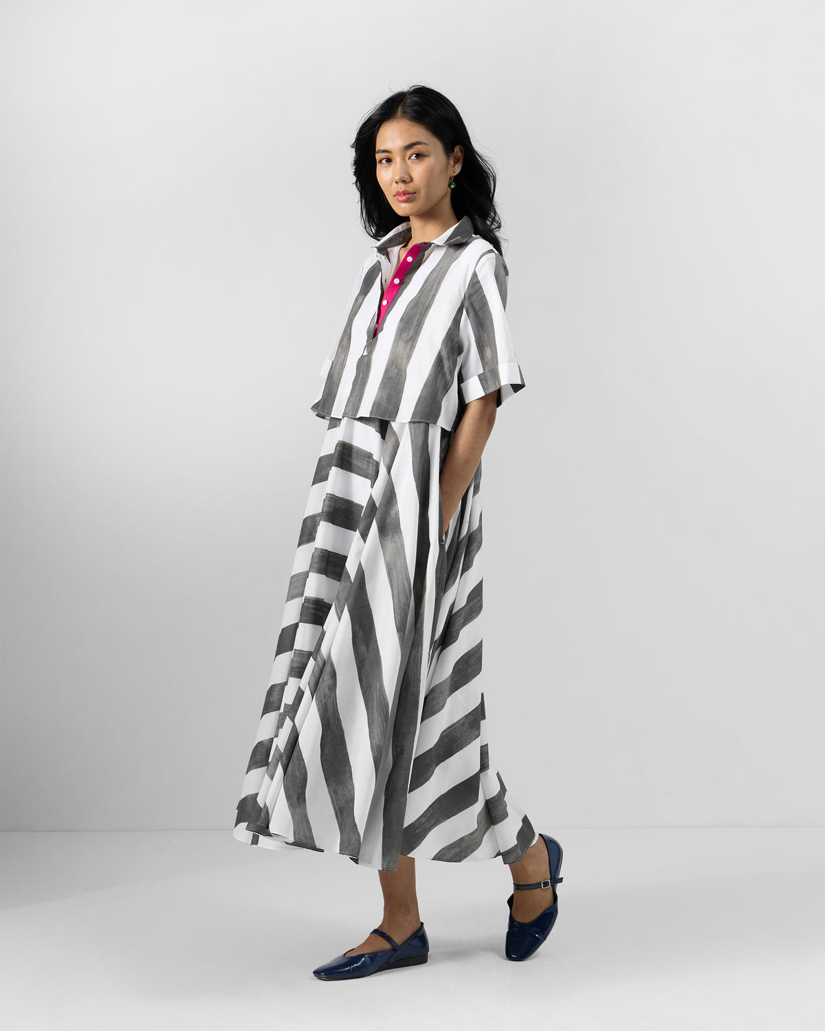 Side view of a charcoal and white striped Kuro Dress with a flared skirt.