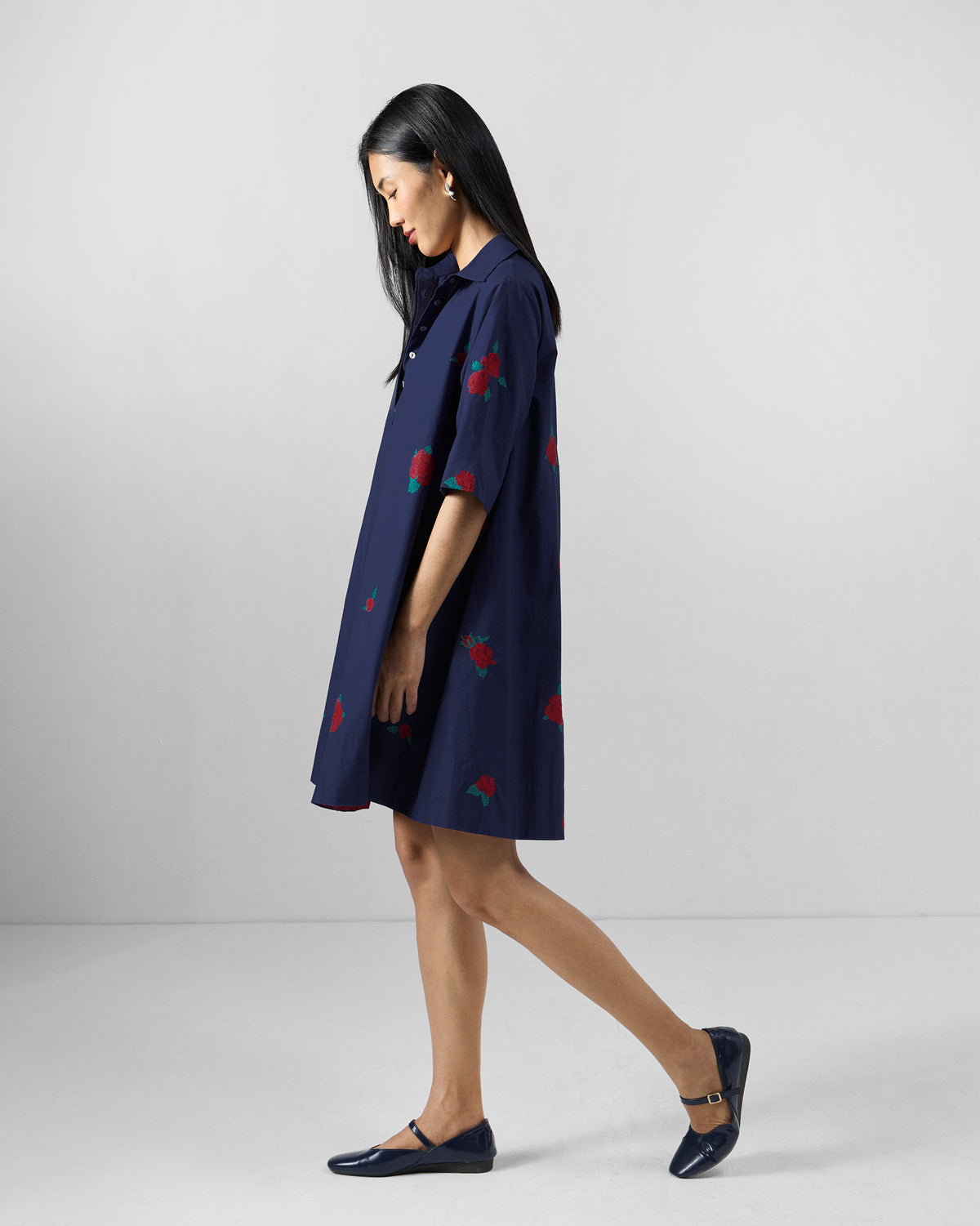 Side view of an ink blue Happy Heart Dress with red floral embroidery.
