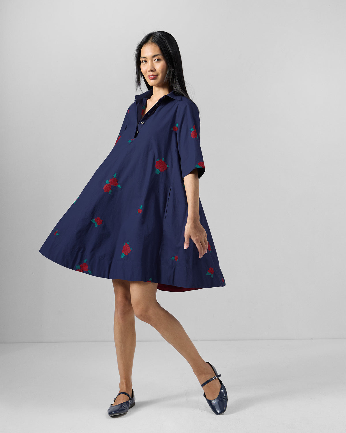 Person wearing an ink blue Happy Heart Dress with red rose embroidery.