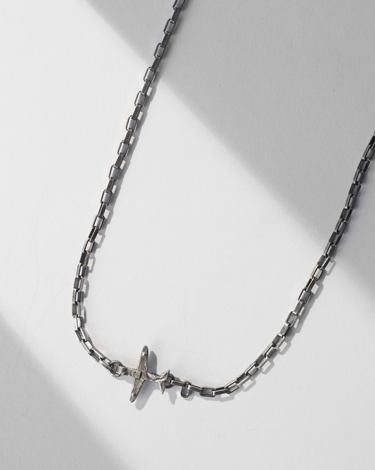 Close-up of the silver Flight Chain with an airplane charm set into the links.