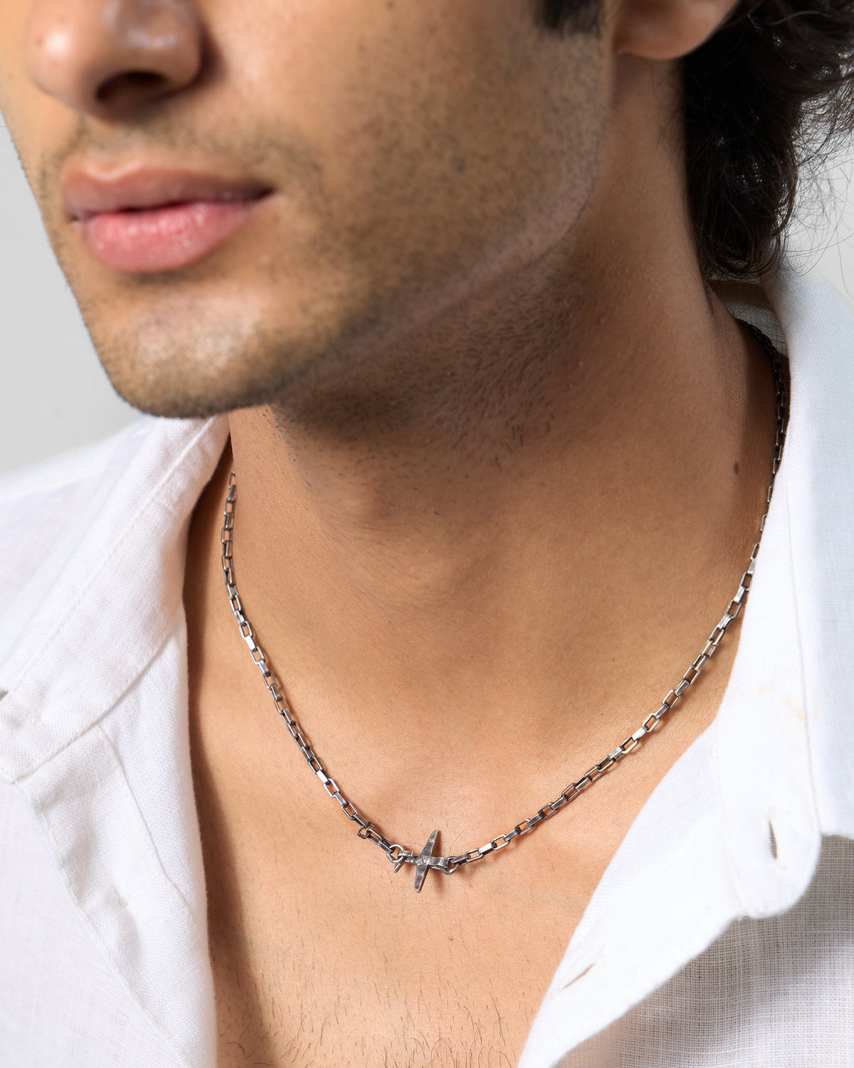 Silver Flight Chain with airplane charm worn at an open shirt collar.
