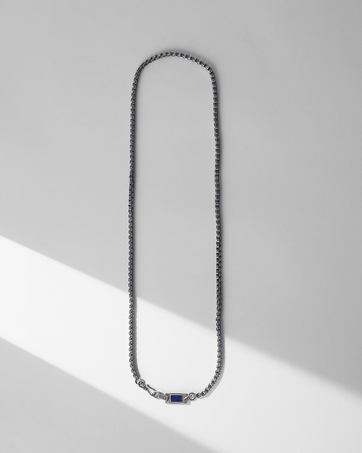 Silver Taro box chain laid flat with a rectangular lapis clasp detail.