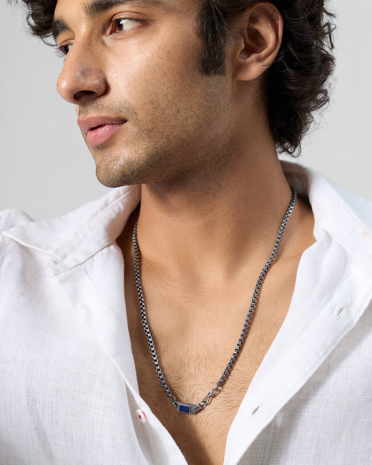 Person wearing a silver Taro chain with a rectangular lapis accent.