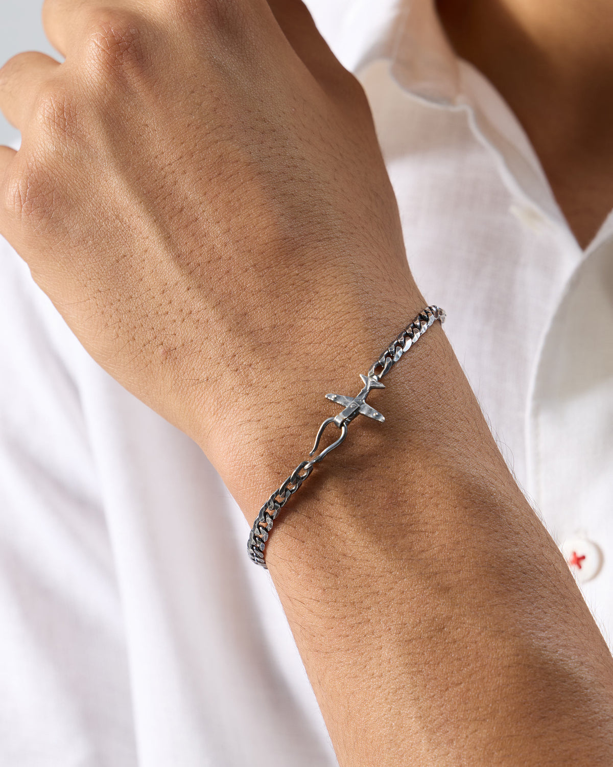 Silver flight bracelet with airplane clasp worn on a wrist.