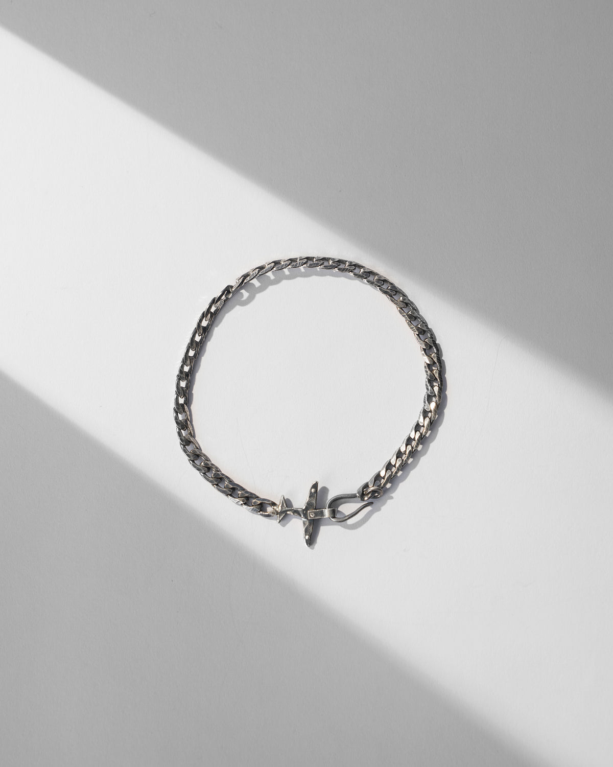 Silver flight bracelet with airplane clasp laid in a circle.