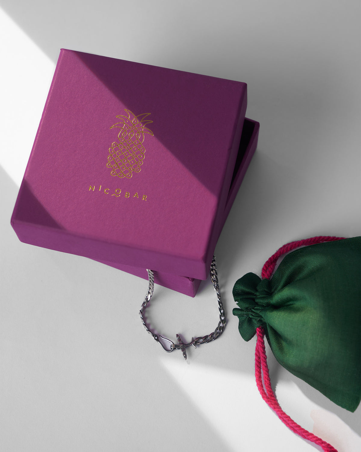 Silver flight bracelet emerging from a plum Nicobar gift box.