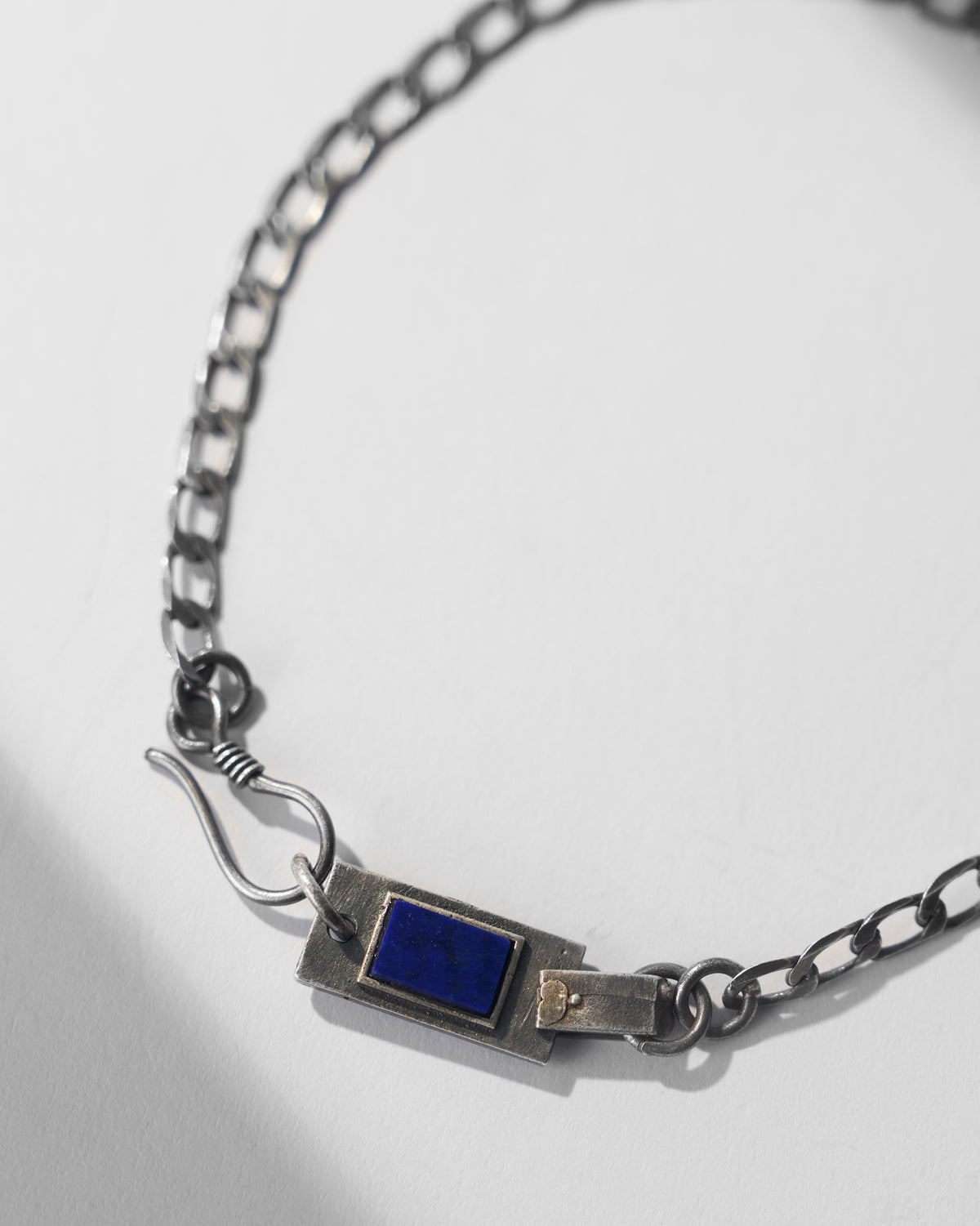 Close-up of a silver Taro bracelet showing the blue stone plaque and hook clasp.