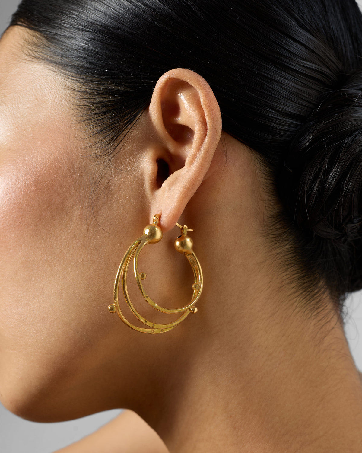 Side profile of gold Celestial balis with triple nested hoops on a person.