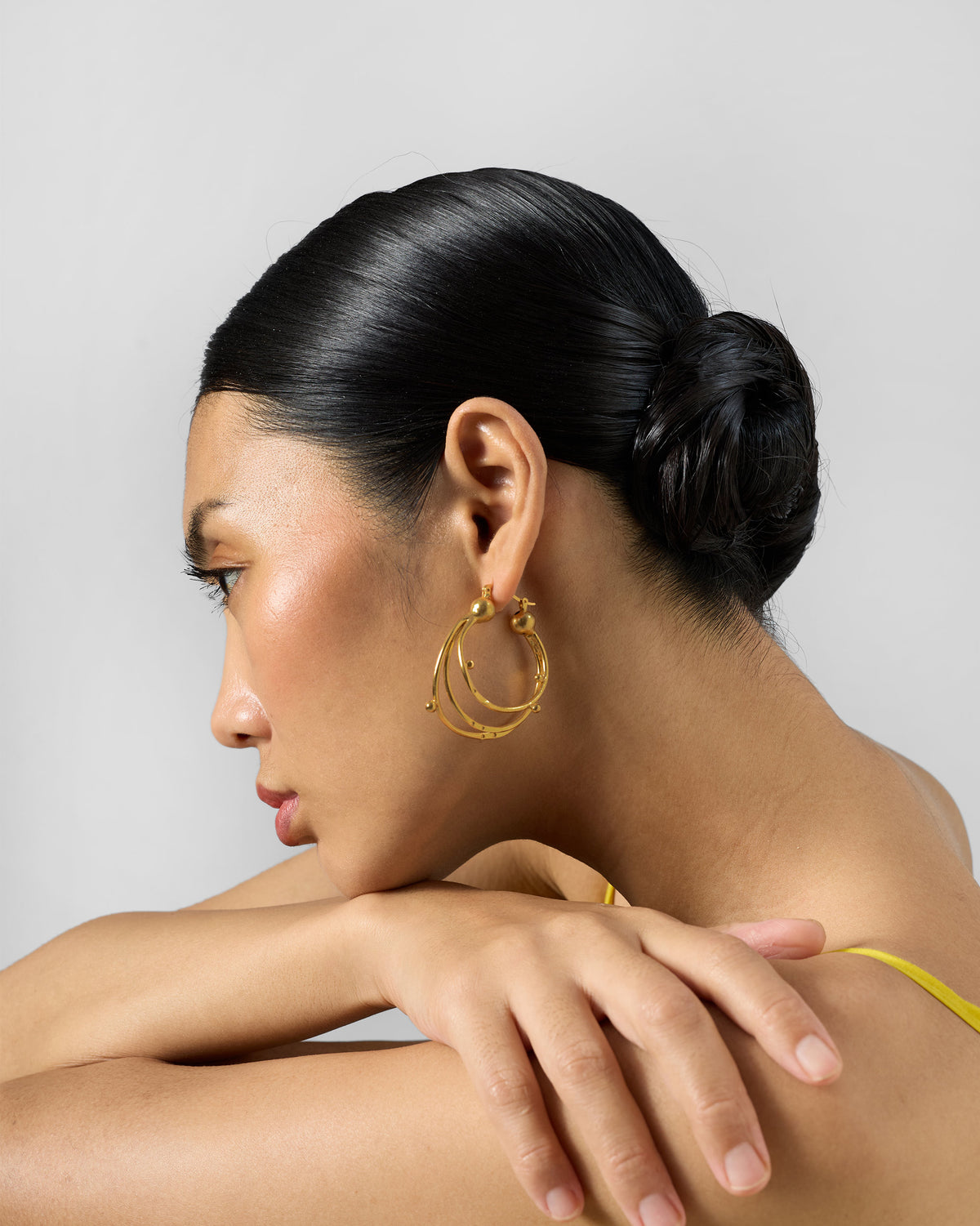 Side profile of gold Celestial balis with layered hoops worn by a person.