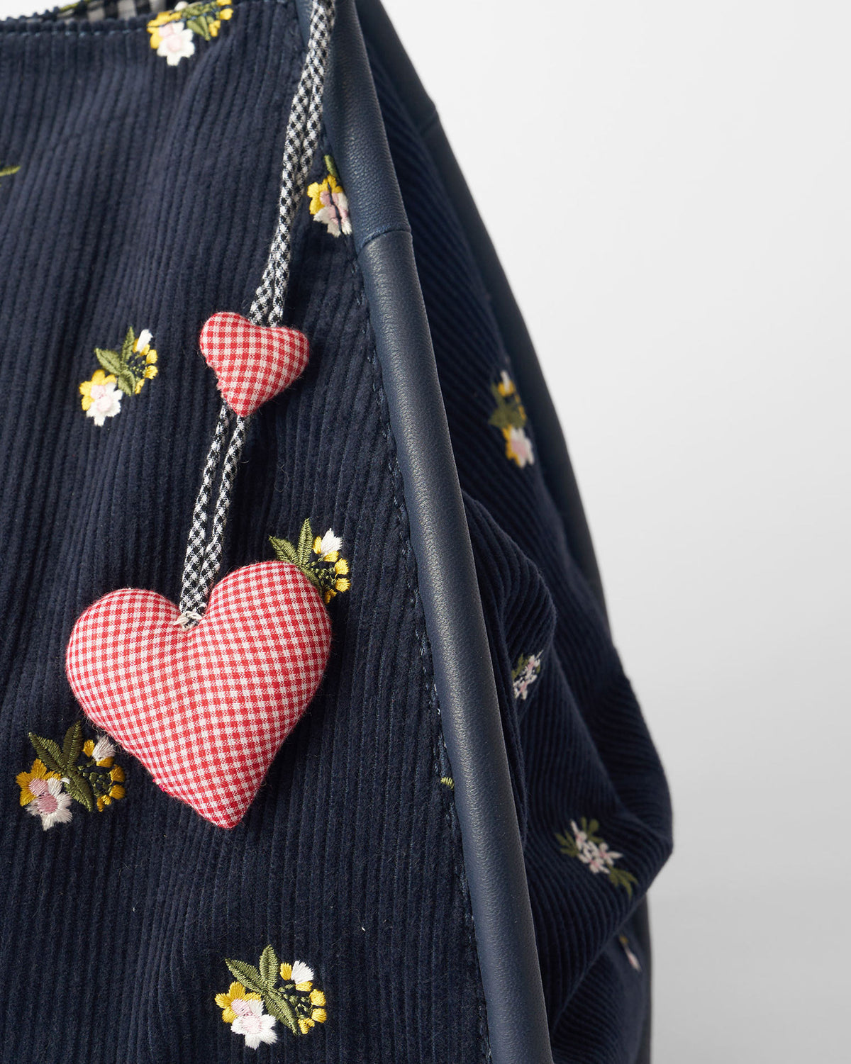 Close-up of gingham heart charms on a navy Ditsy bag.