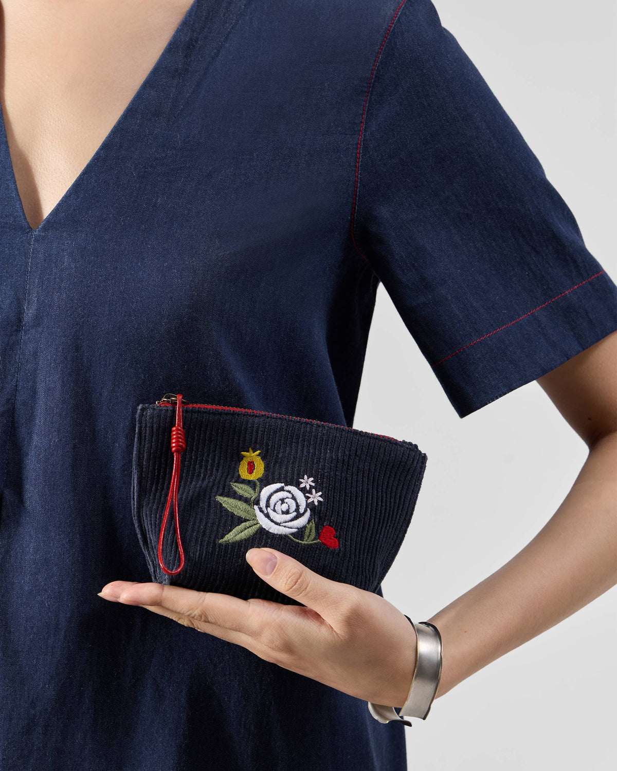 Navy Ditsy coin pouch with floral embroidery held in a hand.