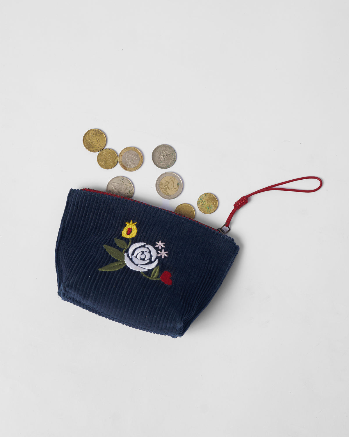 Navy Ditsy coin pouch with floral embroidery beside coins.