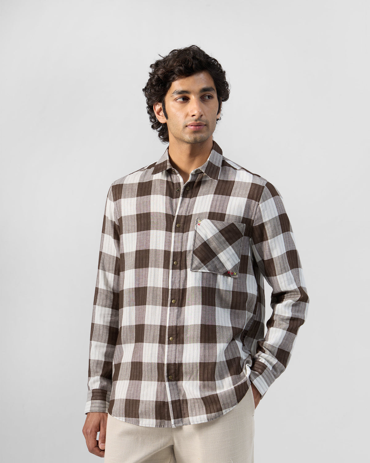 Person wearing a brown check Milaan shirt with a bias-cut pocket.