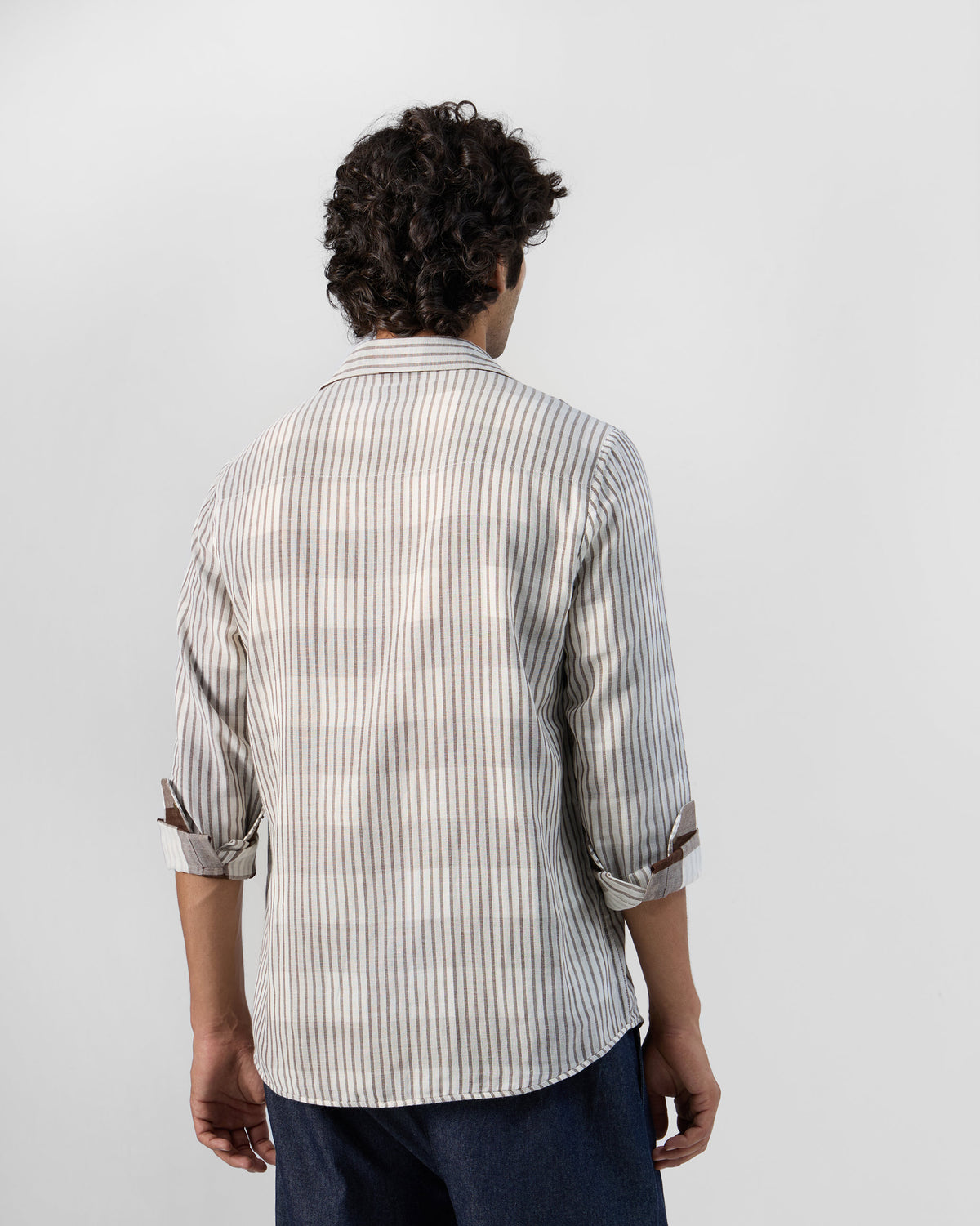 Back of a beige striped Milaan shirt worn by a person.