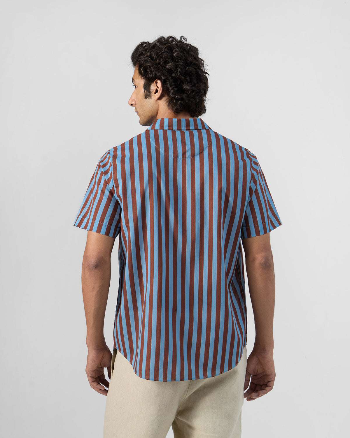 Back of a blue and brown striped Mason shirt worn by a person.