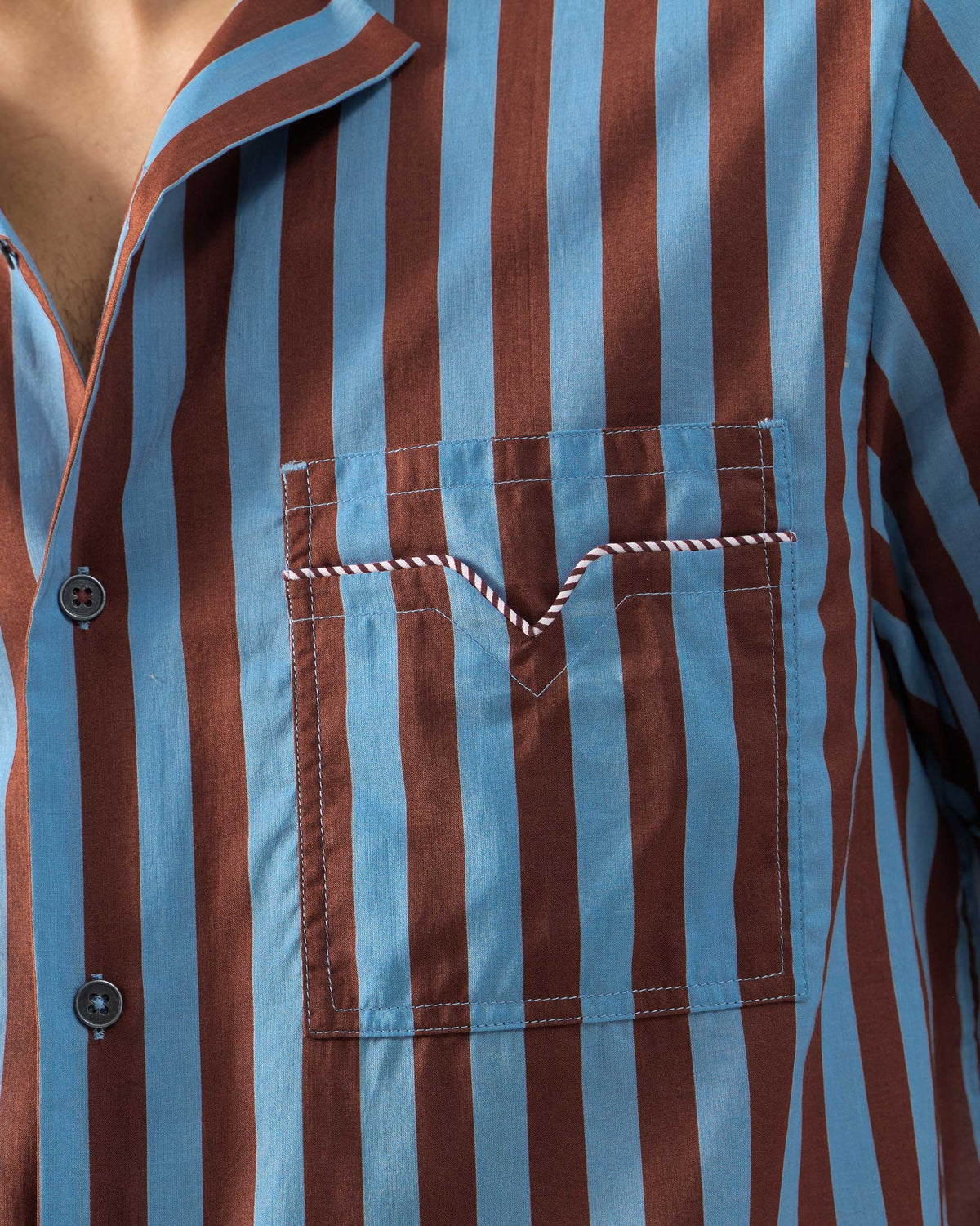 Close-up of a Mason shirt chest pocket with striped piping and aligned blue brown stripes.