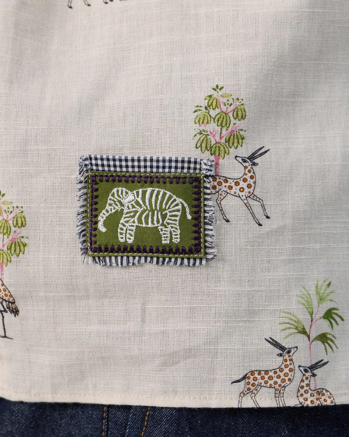 Close-up of an elephant patch on a cream Bena shirt.