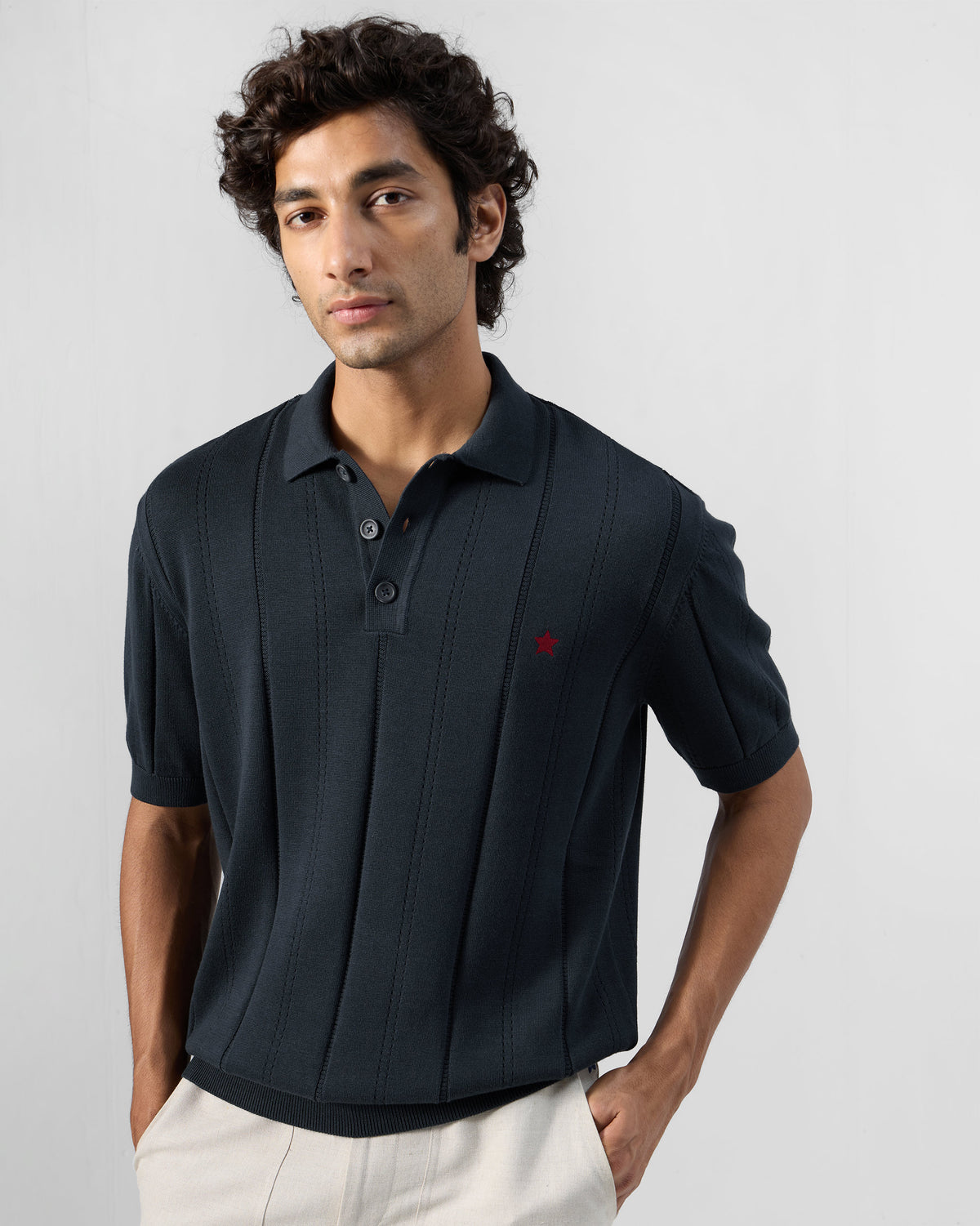 Person wearing a dark navy Midnight polo with a ribbed knit texture and red chest star.