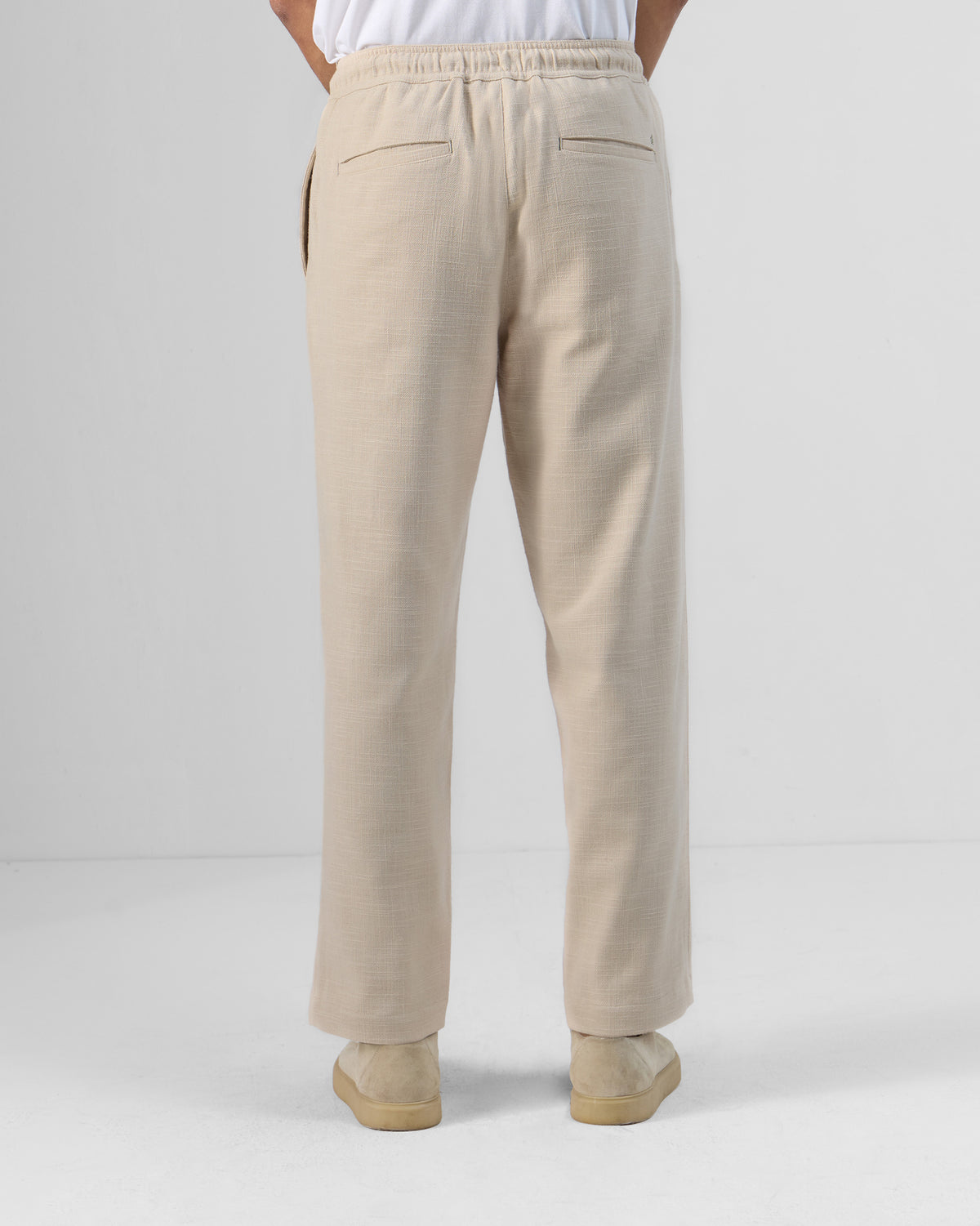 Back of beige Breeze trousers showing an elastic waist and welt pockets.