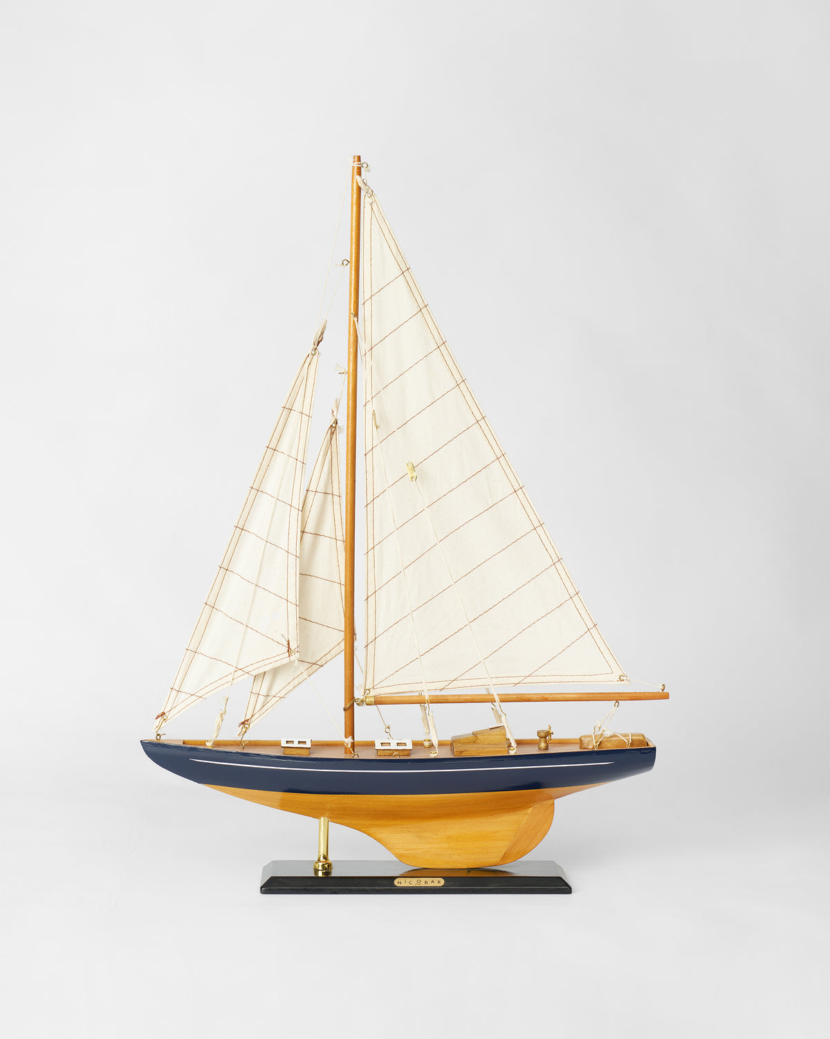 Sail Boat Home Accent with navy hull and cream sails on a black base.