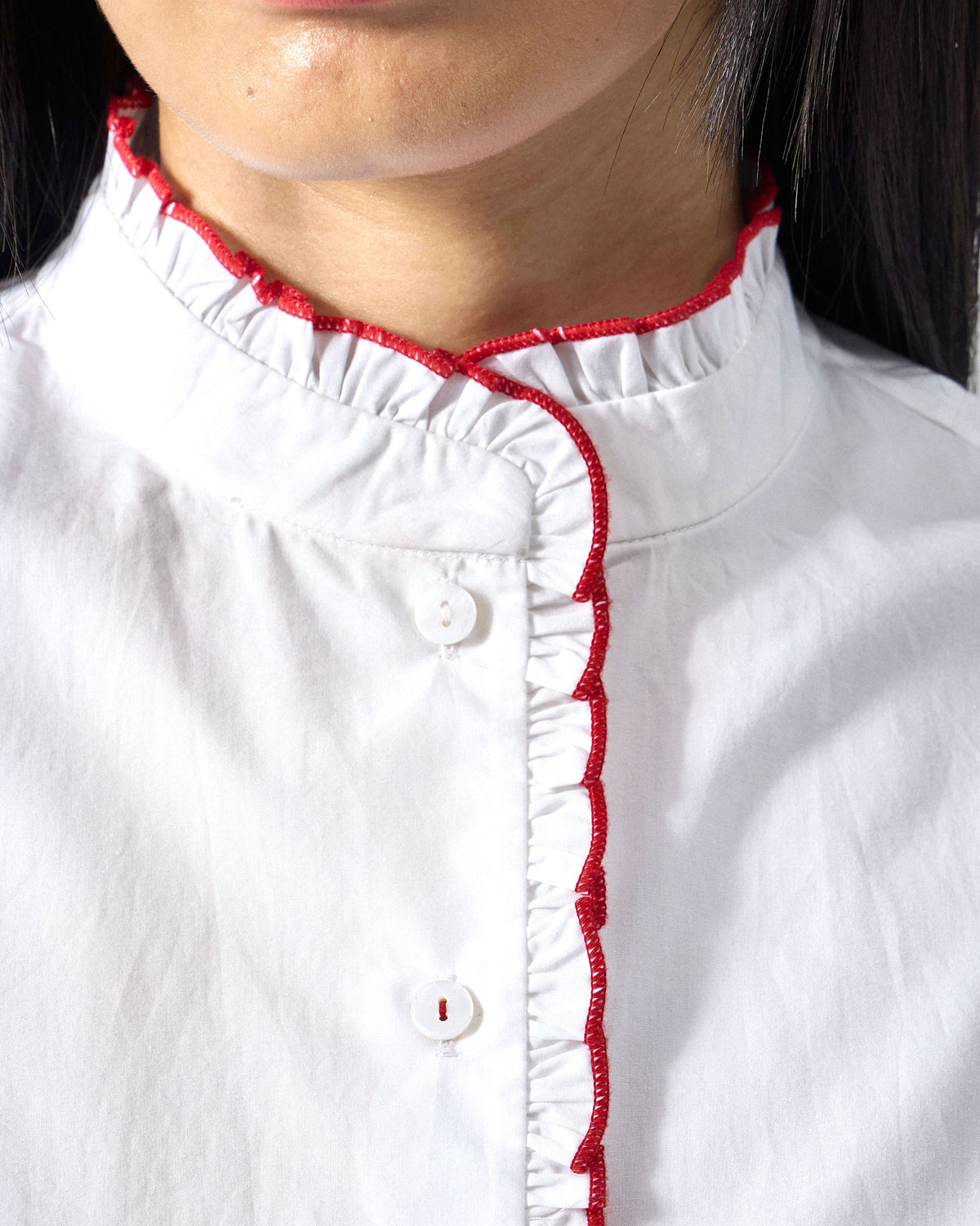 Close-up of a white Sora ruffle shirt showing red-edged ruffles.