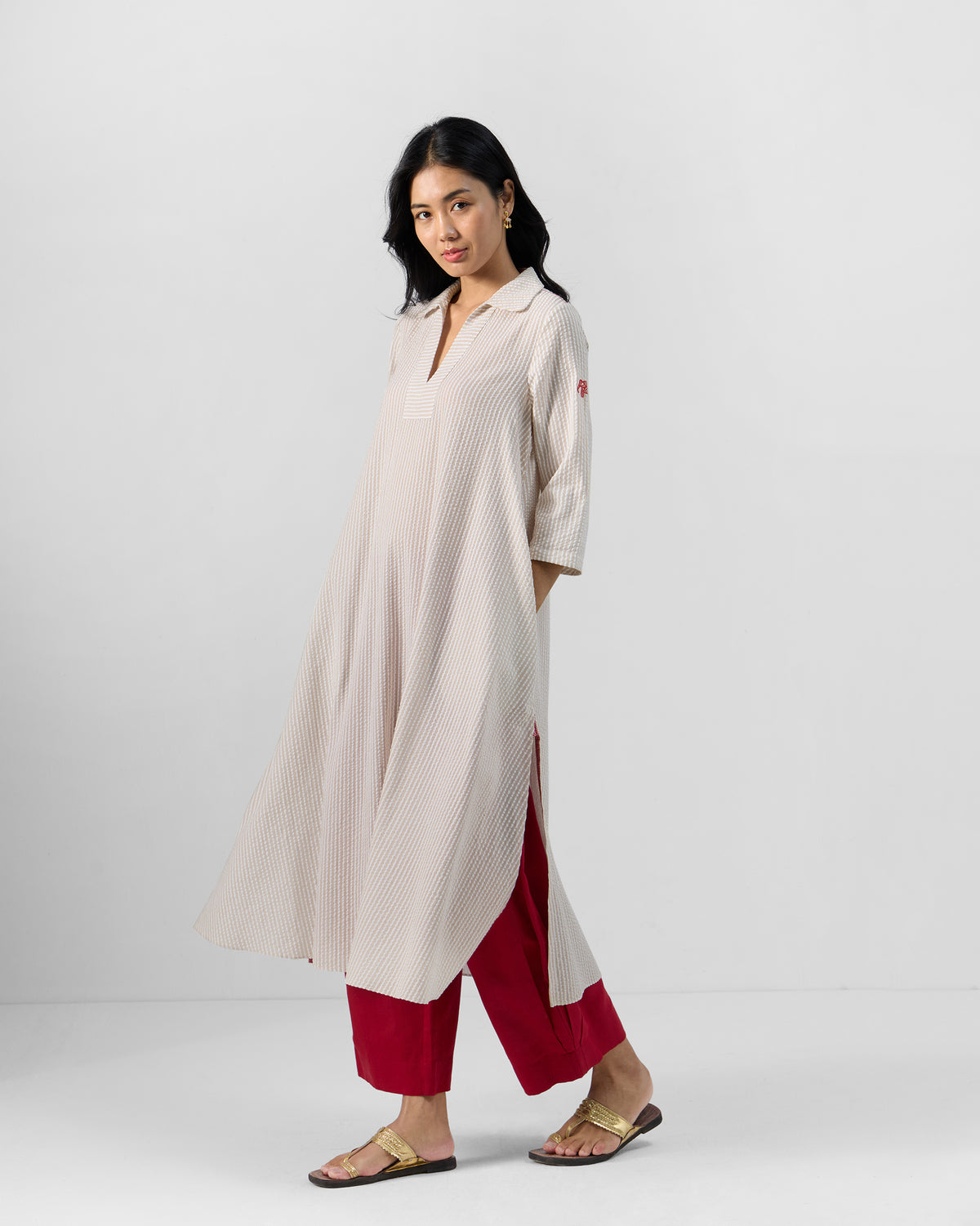 Three-quarter view of a striped Maner seersucker kurta with side slits and pockets.