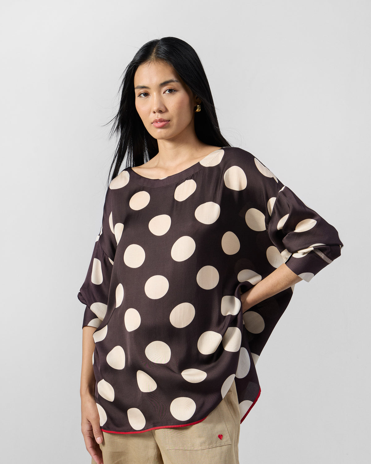 Brown Yava Top with large ivory polka dots and a red hem border.