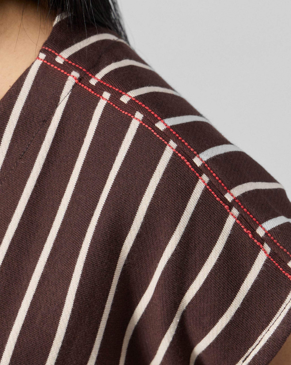 Close-up of red shoulder stitching on a brown and ivory striped Nera kaftan top.